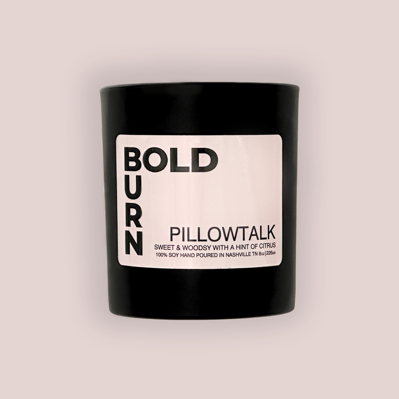 Two wick black candle with white label reading Bold Burn Pillowtalk: Sweet & Woodsy with a hint of Citrus on white background