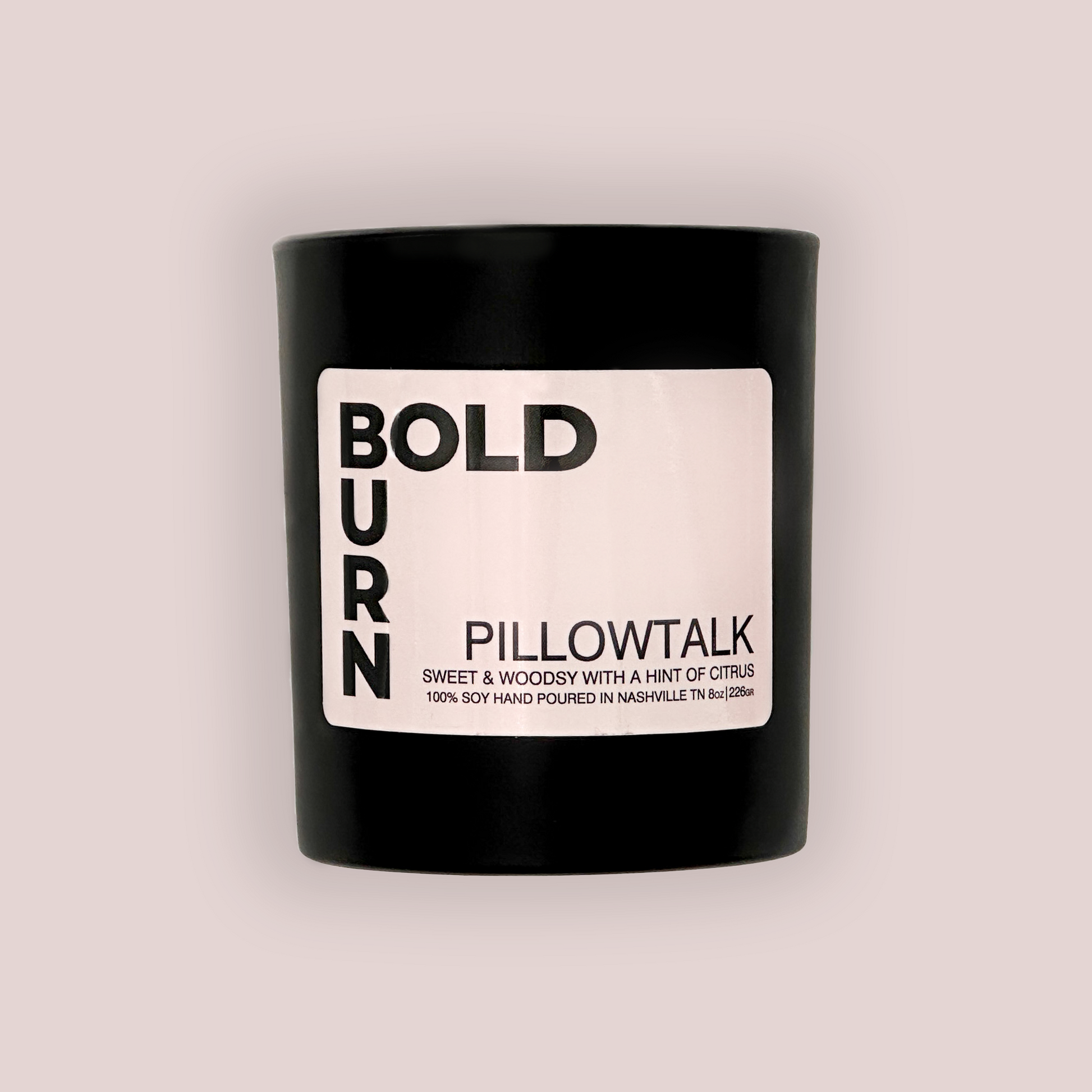 Two wick black candle with white label reading Bold Burn Pillowtalk: Sweet & Woodsy with a hint of Citrus on white background